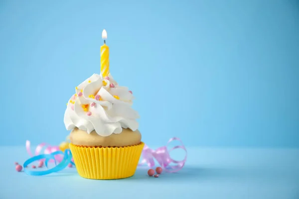 Delicioso cupcake de cumpleaños con vela sobre fondo azul claro . — Foto de Stock