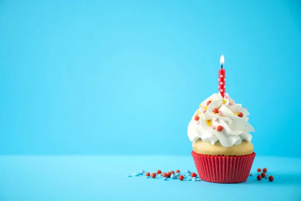 Delicioso cupcake de cumpleaños con vela sobre fondo azul claro . —  Fotos de Stock