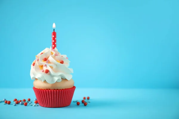 stock image Delicious birthday cupcake with candle on light blue background.