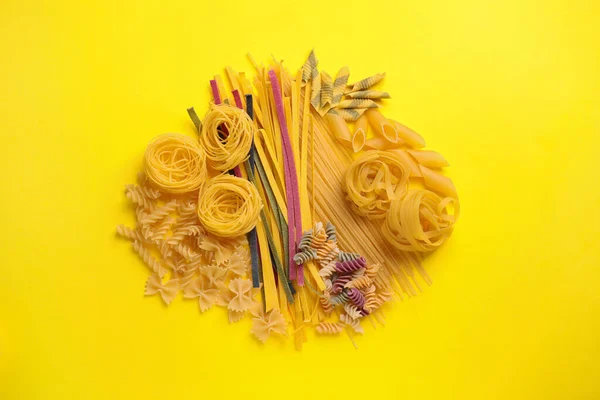Différents types de pâtes sur fond jaune, plat — Photo