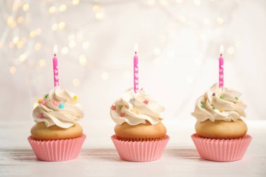 Mavili, beyaz ahşap masada mumları olan doğum günü pastaları.
