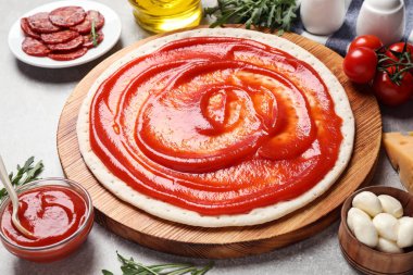 Açık gri masada pepperonili pizza için temel ve taze malzemeler.
