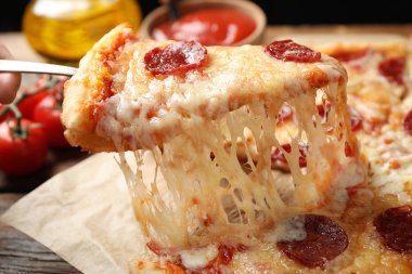 Ahşap masada lezzetli bir biberli pizza dilimi, yakın plan.
