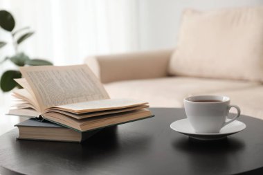 Kitaplar ve bir fincan çay modern kanepenin yanındaki masada. İç mimari