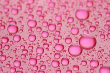 Pembe arkaplanda su damlaları, yakın çekim görüntüsü