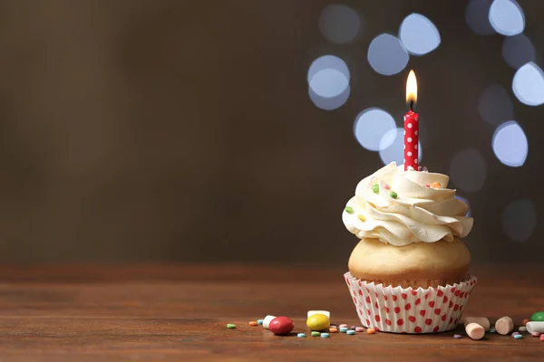 Babeczka urodzinowa ze świecą na drewnianym stole przeciwko rozmytej lidze — Zdjęcie stockowe