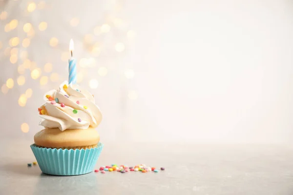 День народження кекс зі свічкою на світло-сірому столі проти розмитих — стокове фото