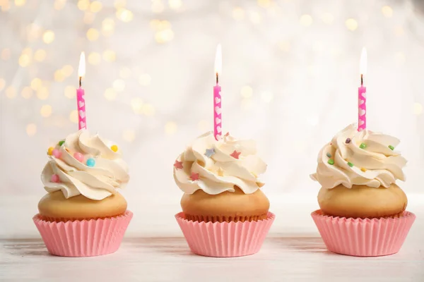 Cupcakes de cumpleaños con velas en mesa de madera blanca contra blu —  Fotos de Stock