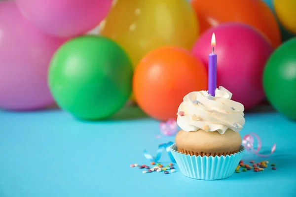 Magdalena de cumpleaños con vela y globos borrosos en el fondo . —  Fotos de Stock