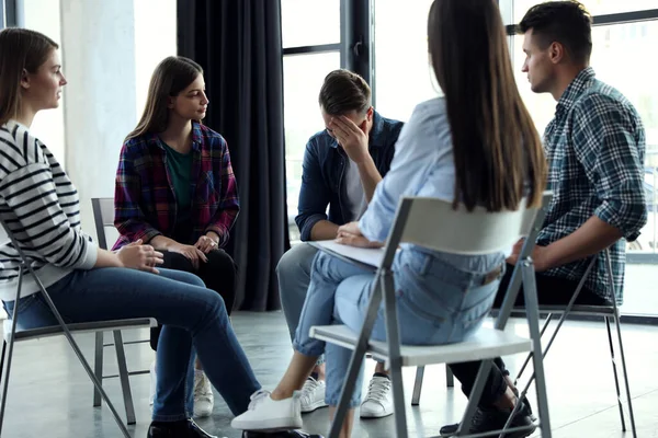 Psychotherapist working with patients in group therapy session indoors