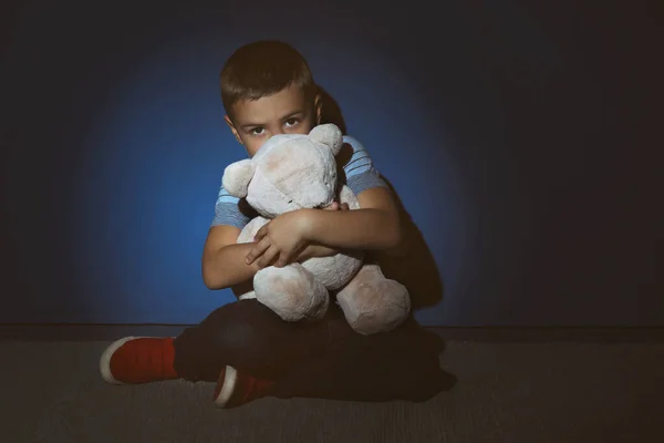 Triste petit garçon avec ours en peluche près du mur bleu. Violence domestique — Photo