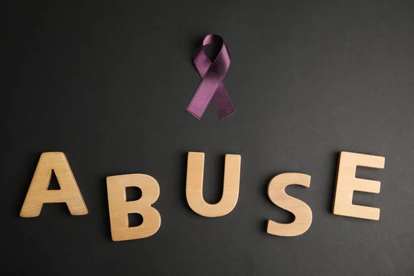 紫のリボンと言葉黒の背景に虐待 フラットレイアウト 家庭内暴力意識 — ストック写真