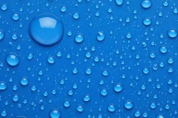 Water drops on blue background, top view