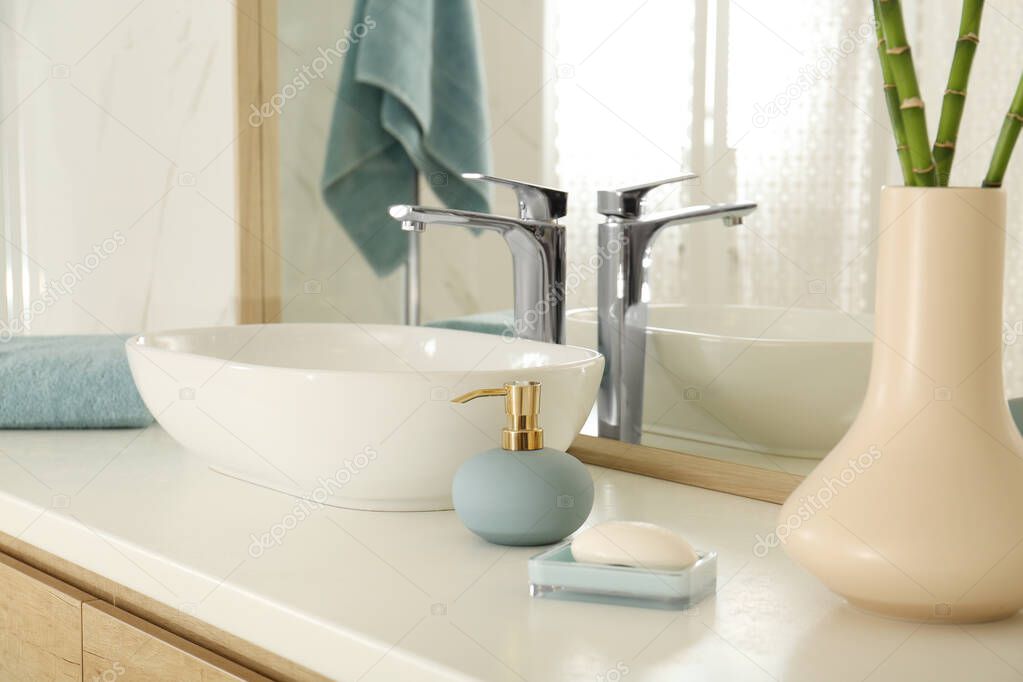 Vessel sink and toiletries near mirror in bathroom