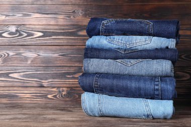 Ahşap masada farklı kot pantolon yığını. Metin için boşluk