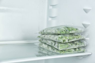 Buzdolabında farklı donmuş sebzeler olan plastik poşetler.