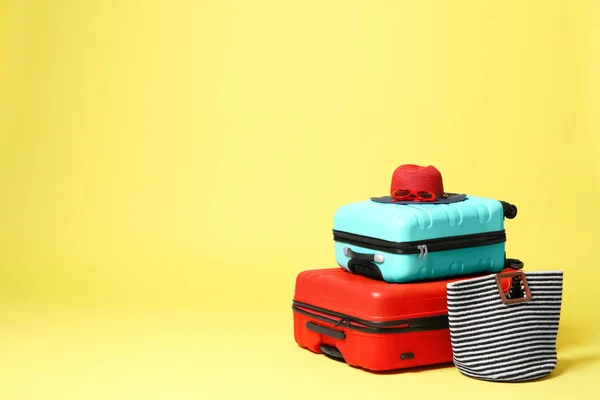 Stylish suitcases with hat and bag on yellow background. Space f — Stock Photo, Image