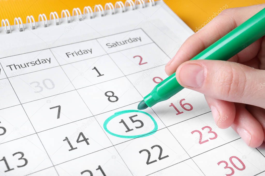 Woman marking date in calendar with felt pen, closeup