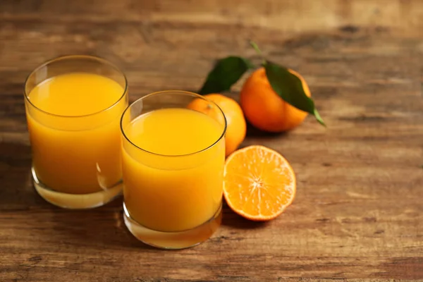 Glasses of fresh tangerine juice and fruits on wooden table — ストック写真