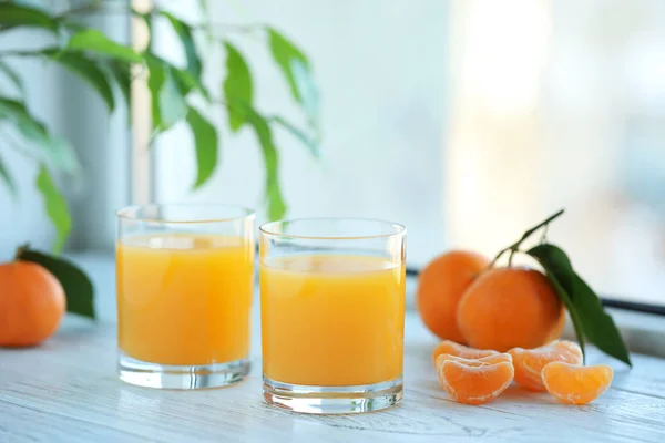 Glasses of fresh tangerine juice and fruits on white wooden tabl — ストック写真