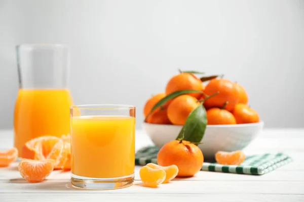 白い木製のテーブルの上に新鮮なみかんジュースや果物のガラス — ストック写真