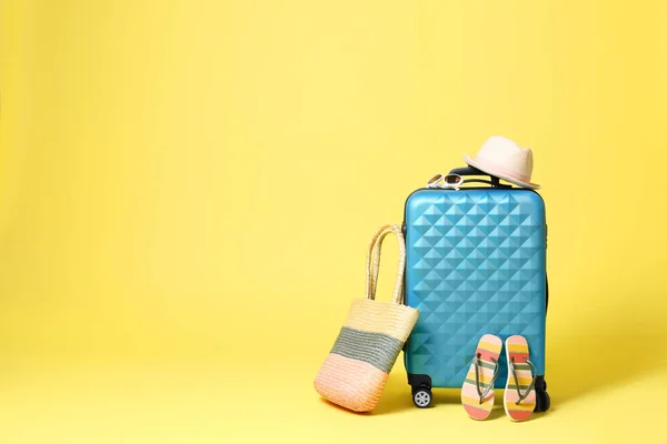 Niebieska walizka z akcesoriami plażowymi na żółtym tle. Kosmos — Zdjęcie stockowe
