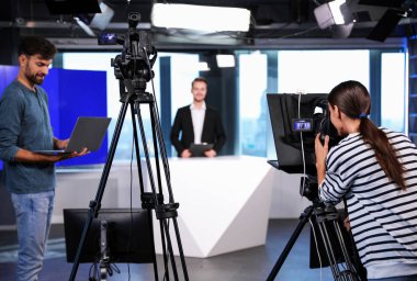 Sunucu, yönetmen ve video kamera operatörü stüdyoda çalışıyor. Haber yayını
