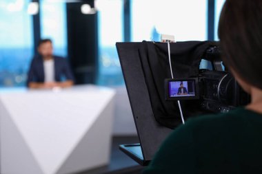 Sunucu ve kamera operatörü stüdyoda çalışıyor. Haber yayını
