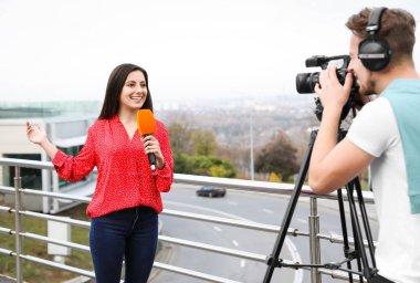 Şehir caddesinde çalışan genç gazeteci ve video operatörü