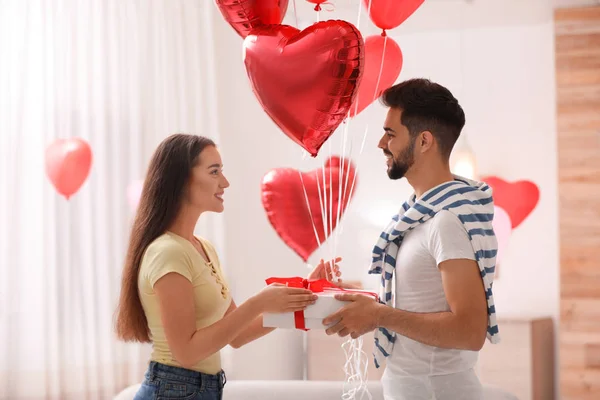 Schönes Junges Paar Mit Geschenkbox Und Herzförmigen Luftballons Wohnzimmer Valentinstag — Stockfoto