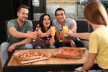 Bir grup arkadaş kafede lezzetli pizzalarla eğleniyorlar.