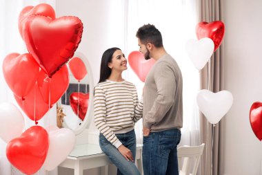 Kalp şeklinde balonlarla dekore edilmiş genç bir çift. Sevgililer Günü kutlaması