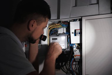 İçerideki elektrik panelini tamir eden fenerli bir elektrikçi.
