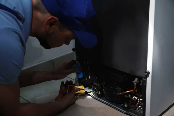 Professionelle Elektriker Mit Taschenlampe Befestigung Kühlschrank Drinnen — Stockfoto