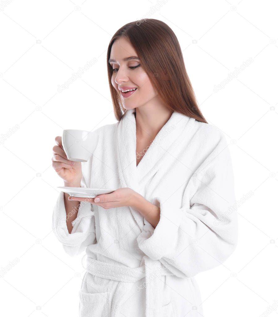 Young woman in bathrobe with cup of drink on white background