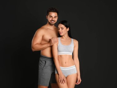 Siyah arka planda gri spor iç çamaşırlı genç çift.