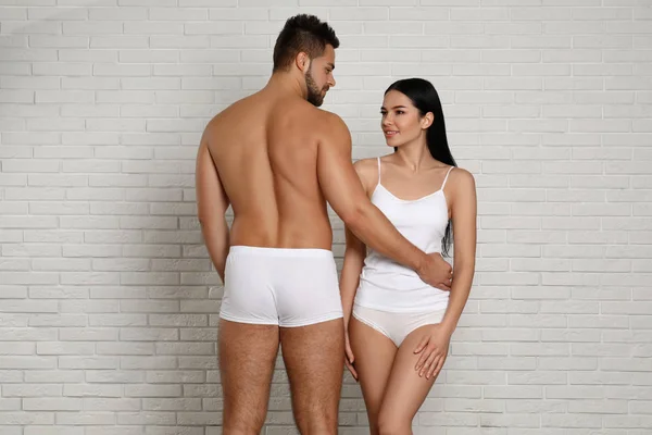 在砖墙附近穿着白色内裤的年轻夫妇 — 图库照片