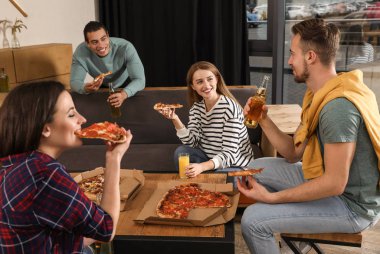 Bir grup arkadaş kafede lezzetli pizzalarla eğleniyorlar.