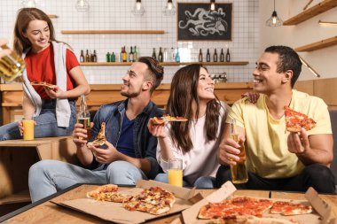 Bir grup arkadaş kafede lezzetli pizzalarla eğleniyorlar.