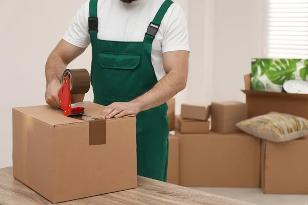 Caixa de embalagem de homem com fita adesiva dentro de casa, close up. Serviço de mudanças — Fotografia de Stock
