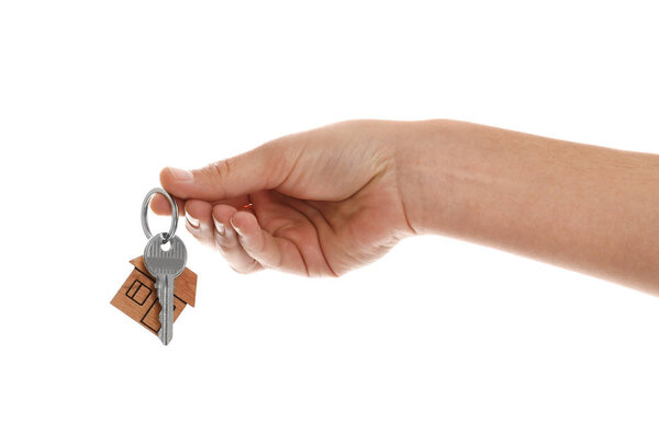 Real estate agent holding house key with trinket on white background, closeup
