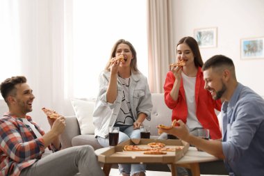 Bir grup arkadaş evde lezzetli pizza yiyorlar.