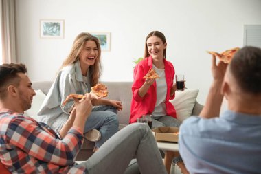 Bir grup arkadaş evde lezzetli pizza yiyorlar.