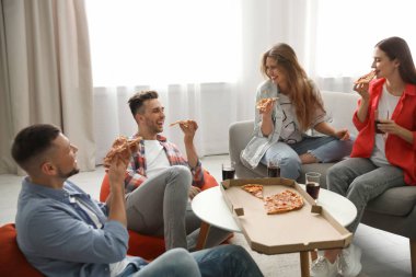 Bir grup arkadaş evde lezzetli pizza yiyorlar.
