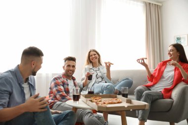 Bir grup arkadaş evde lezzetli pizza yiyorlar.