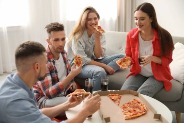 Bir grup arkadaş evde lezzetli pizza yiyorlar.