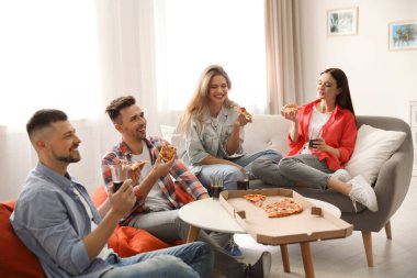 Bir grup arkadaş evde lezzetli pizza yiyorlar.