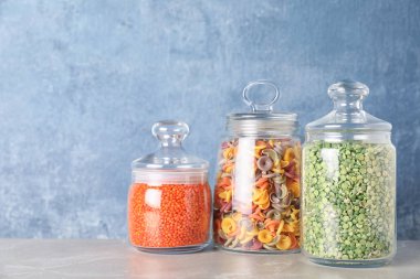 B ışığına karşı gri mermer masada farklı mısır gevrekleri olan kavanozlar.