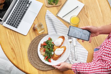Yemek blogcusu öğle yemeğini ahşap masada çekiyor.