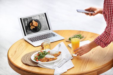 Yemek blogcusu öğle yemeğini içeride, ahşap masada çekiyor.